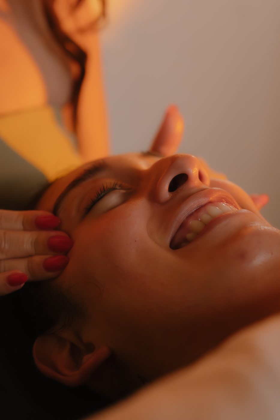Alexis performing a facial massage in warm studio lighting
