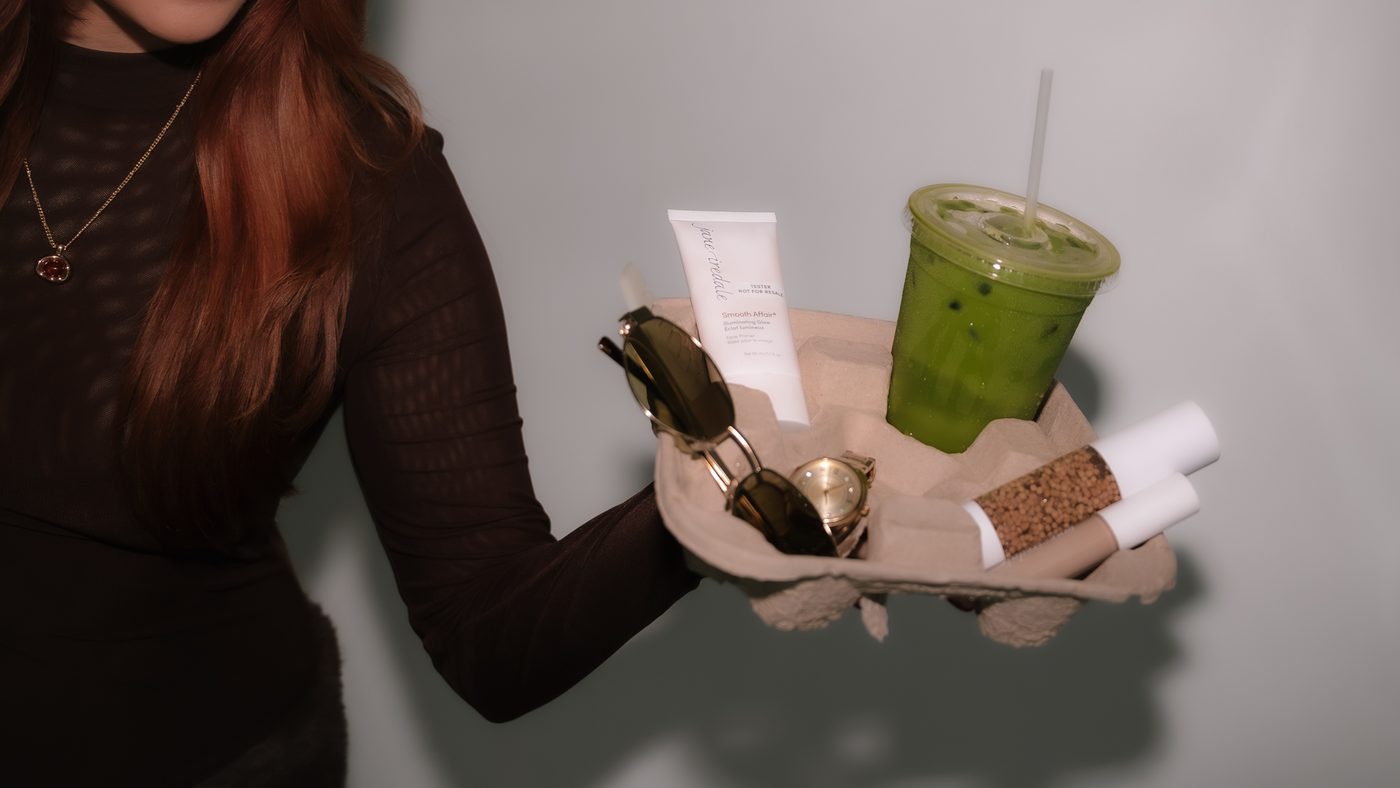 A curated gift tray with skincare, sunglasses, and a matcha latte